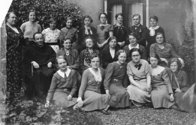 876903 Groepsportret van pater Sebastianus van Nuenen (zittend links) met een groep medewerksters van het Franciscus ...